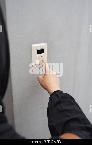 A hand presses a bell button on a wall Stock Photo