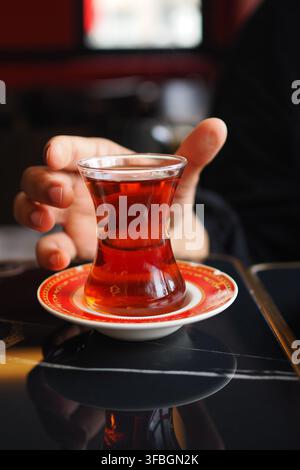 Hand holding a cup of turkish tea on a table Stock Photo
