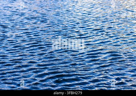 Calm blue water ripples gently across surface. Smooth patterns suggest peaceful, quiet environment. Ideal for backgrounds, travel, or nature-themed de Stock Photo