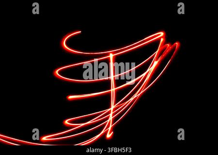 Abstract long exposure photography featuring glowing red light trails and glowing curves creating dynamic patterns and artistic streaks against a deep Stock Photo