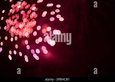 Abstract photography of blurred glowing circles creating a vibrant red and dark backdrop with sparkling bokeh patterns representing festive celebratio Stock Photo