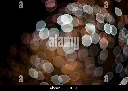 Abstract out of focus sparkling lights creating a magical glowing circular bokeh effect with vibrant multicolored spots against a dark nighttime backg Stock Photo