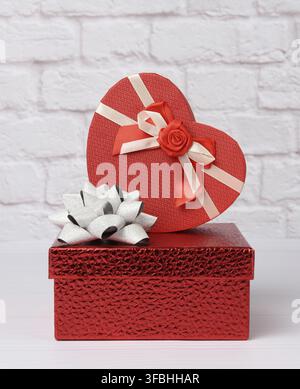 Stack of various red boxes with gifts on white background, festive backdrop Stock Photo