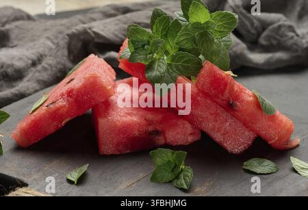 Fresh watermelon sliced ??into triangles with mint leaves on a black wooden board Stock Photo