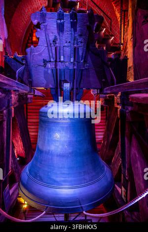 The bell inside the Cathedral of the Holy Spirit hangs from wooden beams. This view shows its large size and the structure supporting it. Light enhances the bell's surface. Stock Photo