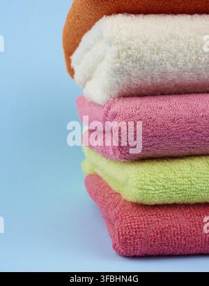 Stack of colored cotton terry folded towels on a blue background, close up Stock Photo