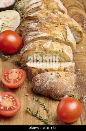 Sliced ??baguette and red cherry tomatoes on a wooden board Stock Photo