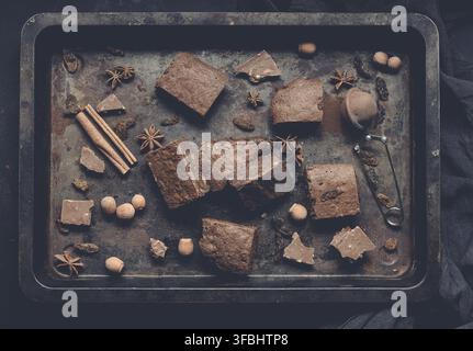 Pieces of baked chocolate brownie pie in a metal baking sheet on a black table, top view Stock Photo