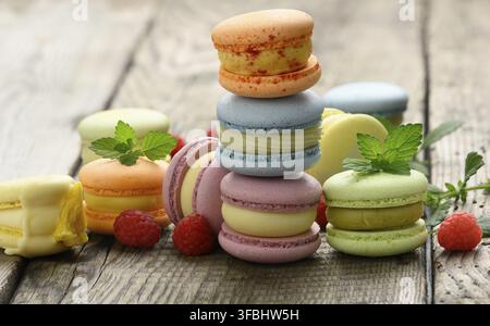 Stack of baked multicolored macarons and different flavors on a gray wooden table, delicious dessert, close up Stock Photo