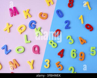 Plastic multi-colored numbers and letters of the English alphabet on a blue-violet background, top view, back to school Stock Photo
