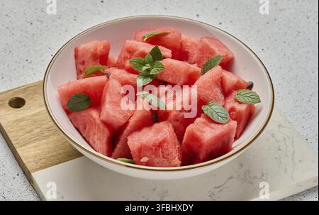 Ripe watermelon slices with mint leaves in a white round plate on the table Stock Photo