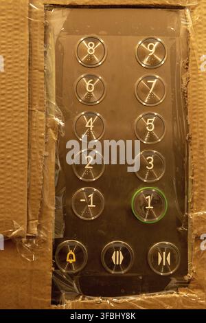 Cardboard wrapped lift elevator control panel and buttons with missing 0 level. Protected lift elevator during construction works Stock Photo
