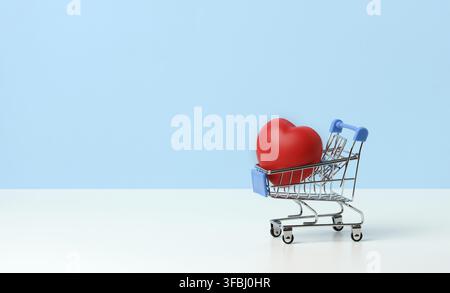 Red heart in a miniature metal trolley from the store on a blue background. Organ donation, transplant concept, copy space Stock Photo