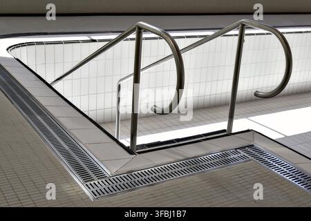 Indoor pool with railing for descending, indoor pool without water with railing to the stairs, white tiles on the indoor pool floor, chrome steel shee Stock Photo