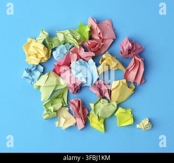 Crumpled multi-colored paper stickers, top view, blue background, close up Stock Photo