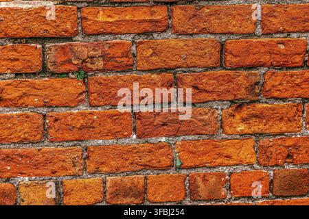 Old brick wall of red color, damaged masonry as abstract background composition. textured surface of stucco texture Stock Photo