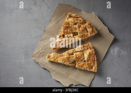 Two baked pieces of apple pie on brown paper, top view, gray background Stock Photo