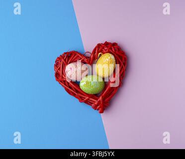 Multicolored decorative Easter eggs decorated with sequins on a blue purple background, top view Stock Photo