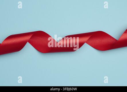 Twisted silk red ribbons for decoration on a blue background, top view Stock Photo