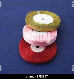 Twisted red, pink, golden silk ribbons on a blue background, element for the designer, close up Stock Photo