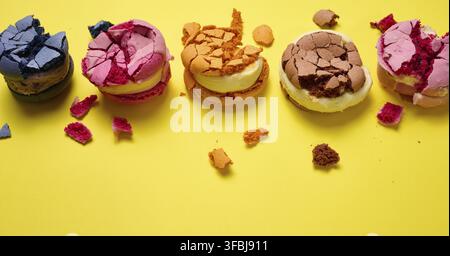 Broken round macarons with crumbs on a yellow background, delicious dessert, top view Stock Photo