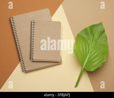 Stack of spiral open notebooks with blank brown sheets on a beige background, top view Stock Photo