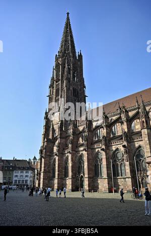 The imposing tower of Freiburg Minster made of red sandstone, taken from Muensterplatz with passers-by in the foreground, impressive Gothic architectu Stock Photo