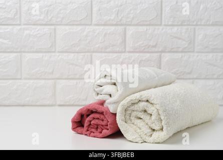 Clean white rolled terry towels on white shelf, bath interior Stock Photo