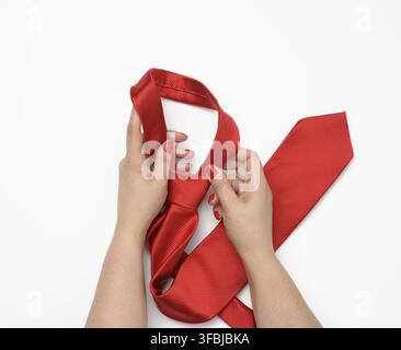 Two female hands hold a red silk tie on a white background Stock Photo