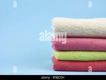 Stack of colored cotton terry folded towels on a blue background, copy space Stock Photo
