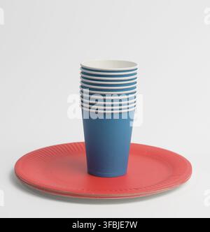Stack of blue paper cups and red round plates on a white background. Plastic rejection concept, zero waste Stock Photo