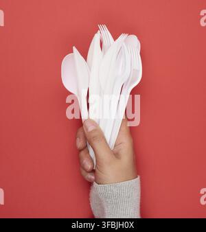 Stack of plastic forks and spoons on red background, close up Stock Photo