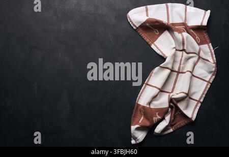 Folded linen linen kitchen towel on a black background, top view. Copy space Stock Photo