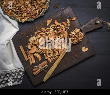 Dried pieces of apples in an iron plate and on a brown wooden board, top view Stock Photo