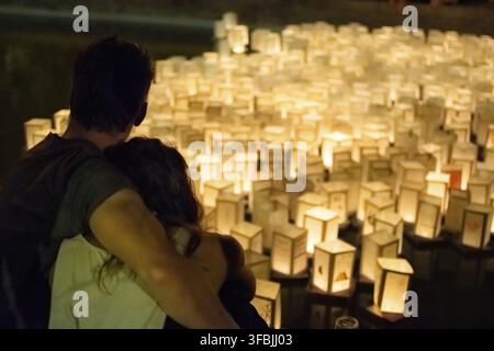 Image of Embracing couple contemplating Paper Lanterns on Water as Asian evening event Stock Photo