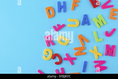 Plastic multi-colored letters of the English alphabet on a blue background, top view, back to school, copy space Stock Photo