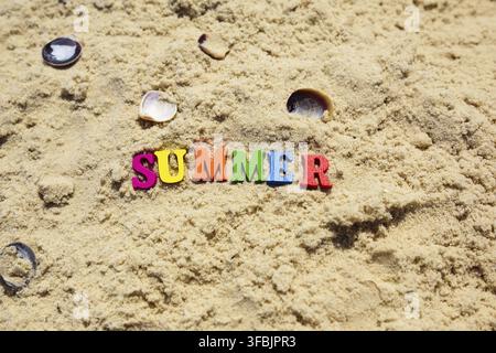 Inscription summer on sand with seashells of multicolored wooden letters, top view Stock Photo