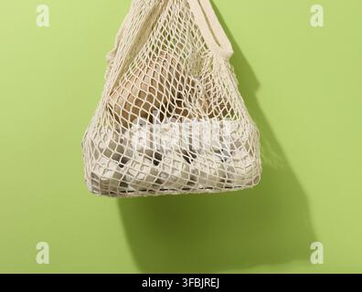 Textile bag with paper cups hanging on a green background. Refusal from plastic bags Stock Photo
