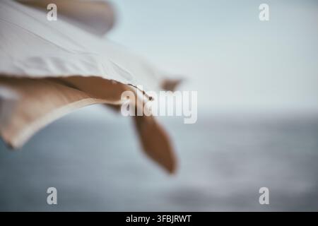 Close-up view of white fabric panels of a beach parasol with soft blurred sea and sky in the background, creating a calm atmosphere. Stock Photo