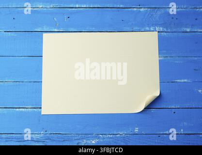 Blank white sheet of paper with a curled corner on a blue wooden background Stock Photo
