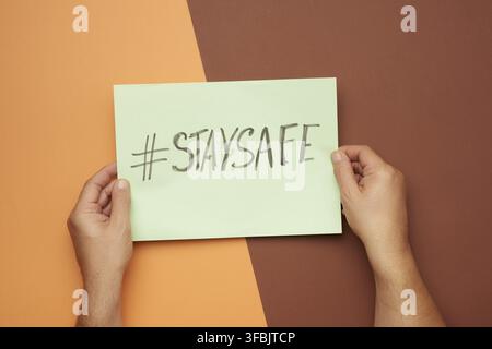 Two man hands holding poster with the inscription stay safe, concept of self-isolation during a pandemic and epidemic Stock Photo