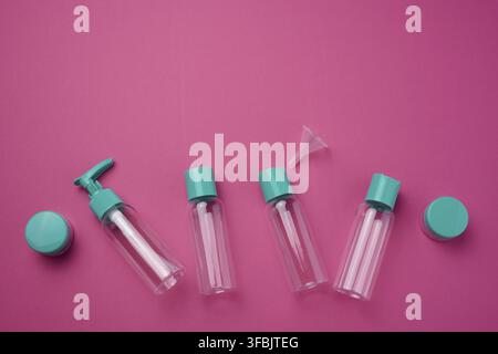 Various transparent empty plastic bottles and jars for cosmetics on a pink background, top view Stock Photo
