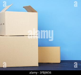 Stack of cardboard boxes of brown kraft paper on a blue wooden table, moving concept Stock Photo