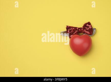 Red rubber heart on a yellow background, top view Stock Photo