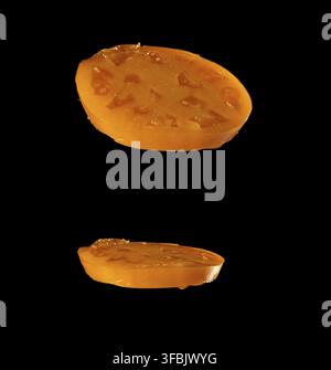 Two slices of yellow ripe tomato isolated on black background, close up Stock Photo