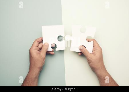 Male hand holding big paper white blank puzzles on a blue background, concept of business Stock Photo