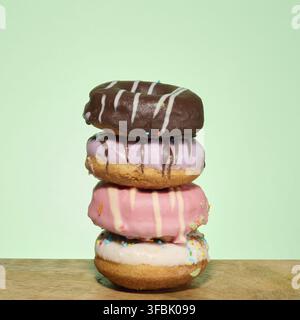 Stack of donuts with different toppings and glazes, green background Stock Photo