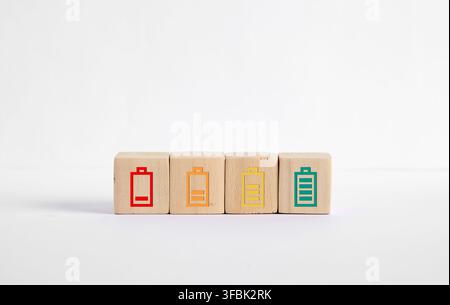 Wooden blocks showing battery charge levels from empty to full as colored icons on white studio background, minimal concept image Stock Photo