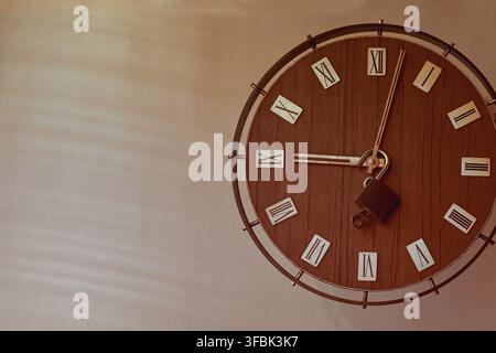 Old clock with Roman numerals on the dial with a padlock on the hands. Start of work time, clock and padloc Stock Photo