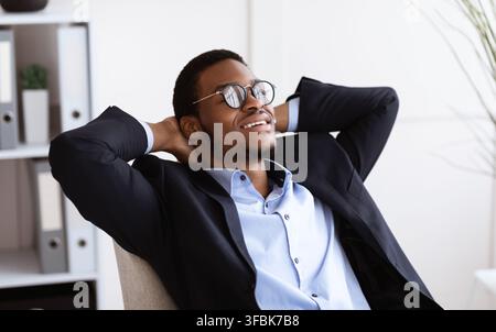 Closeup of relaxed black businessman wearing glasses resting in office Stock Photo